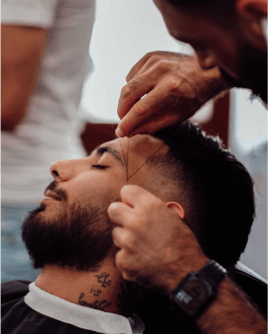 Ein Barber bringt Deine Augenbrauen mit der Fadentechnik in Form, während Du entspannt im Stuhl liegst.